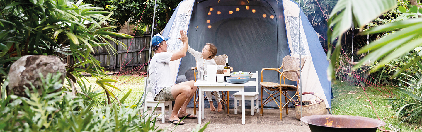 Vater sitzt mit Kind an Tisch vor Zelt