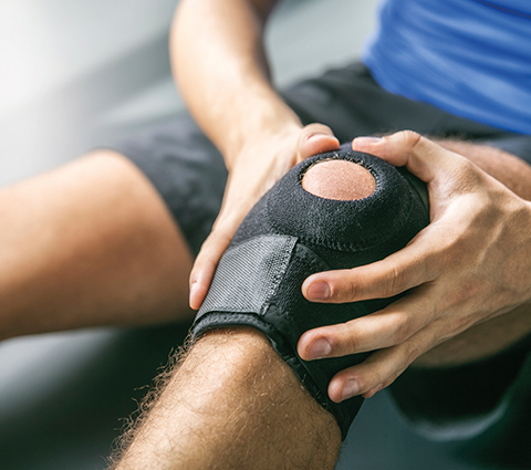 Mann legt sich eine Kniebandage an