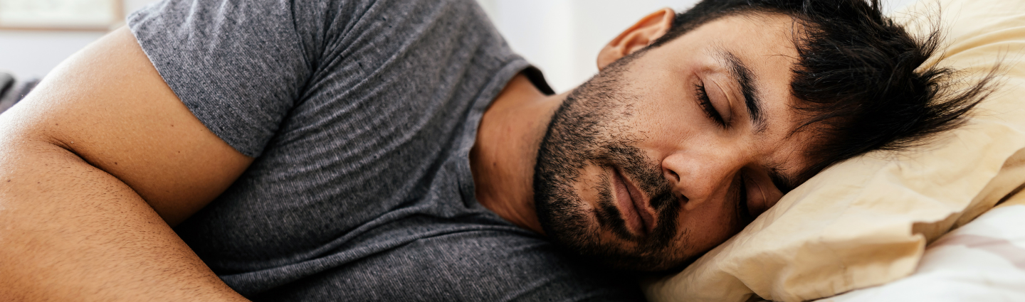 Mann tief schlafend im Bett.